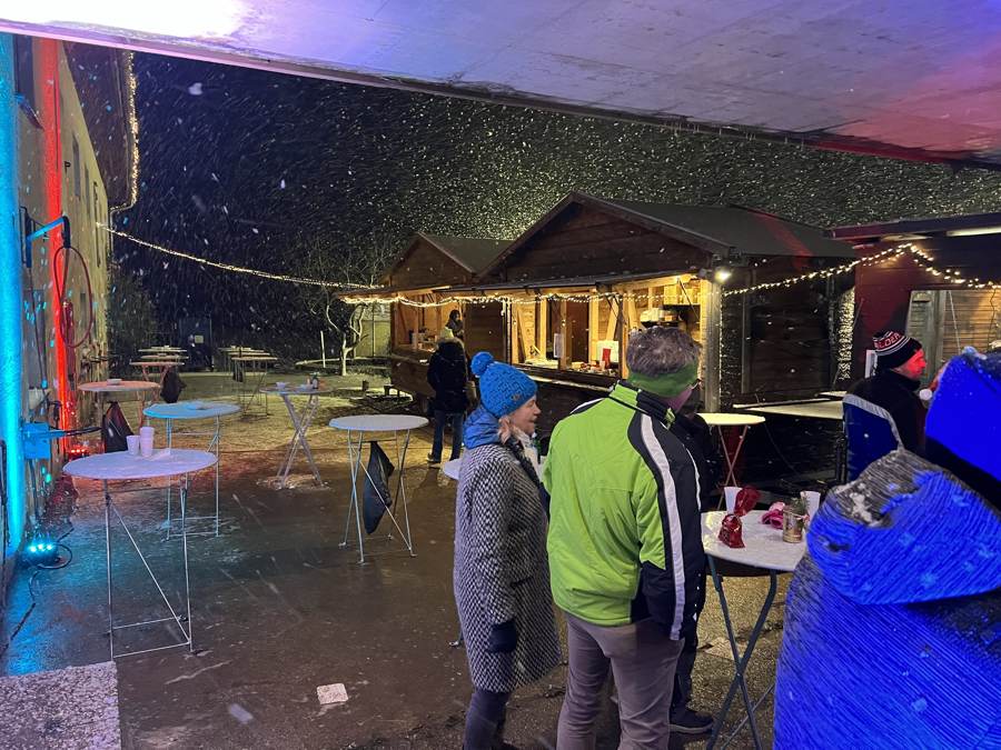 Pferdeweihnacht am Pierhubergut: Holzhütten mit Lichterketten im Schneefall